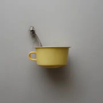 A discarded metal measuring cup in Utility laundry room corner. The cup is repeatedly found slightly off its designated hook. Dust motes suspended in yellow light