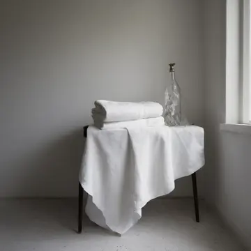 Stacked folded linens in Utility room corner. The towels are being meticulously rearranged after a deep cleaning cycle. White cotton fibers