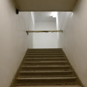 The fire extinguisher cabinet in Sublevel utility stairwell. A routine inspection of shared vertical transit space. Yellowed caution tape near the railing