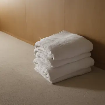 Stack of folded towels in Linen closet corner. A pile of textiles is subtly altering the air quality around it. Dust motes catching faint light