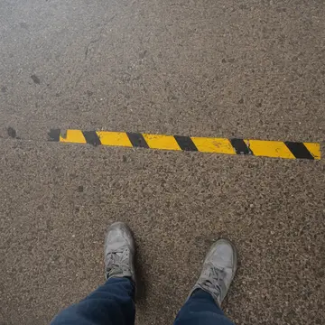 Gum spot on concrete in Train station platform. Passengers navigate around an old, sticky patch of gum. Yellowed warning tape