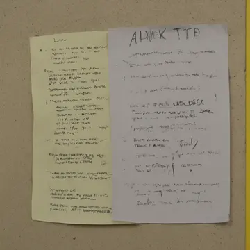 Dry-erase marker in Community notice board alcove. The marker writes faintly on the corner of a posted flyer. Faded yellow sticky notes