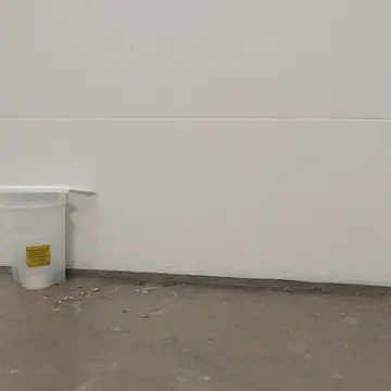 The main service counter surface in Utility room adjacent to transit ticketing. Cleaning crew finishing end-of-day wipe-down. Damp floor tiles reflecting overhead light