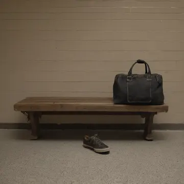 Overstuffed canvas duffel bag in Train station waiting room bench. Waiting for an unnamed person who is late, while the bags and tickets accumulate on the hard surface. Scuffed...