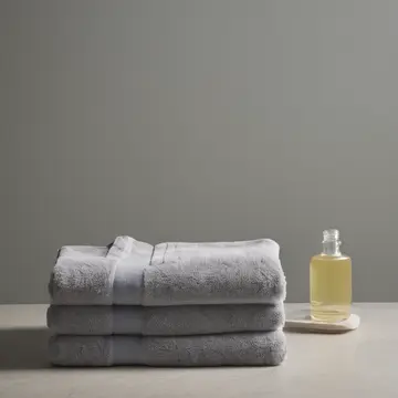 Stacked linen towels in Bathroom utility closet. A morning routine is interrupted by an unfamiliar arrangement of household goods. Soap dispenser with yellowed label