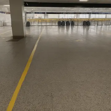 Unused luggage cart in Airport departure lounge concourse. The carts are parked in a tight, staggered line near an empty service door. Scuff marks on polished tile floor