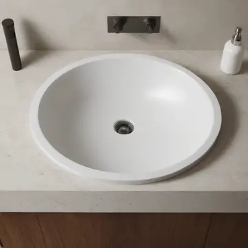 A single, unused ceramic mixing bowl in Kitchen counter near sink. The room is paused mid-preparation for a meal that will not happen. Damp porcelain rim