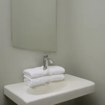 Stacked linen towels in Small utility bathroom. Morning routine of folding and airing out. Slight film on the porcelain sink basin
