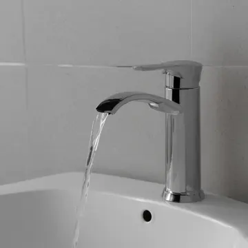 The industrial soap dispenser in Utility kitchen sink area. Night operator finishing end-of-day cleaning log. Chrome faucet dripping condensation