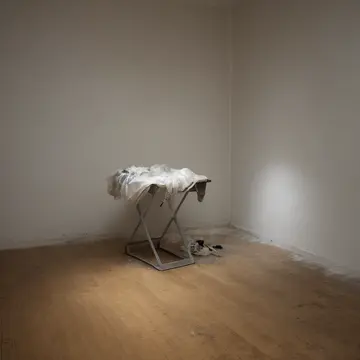 A single abandoned shopping bag in Retail store fitting room area. The routine of folding and stacking merchandise is interrupted by an item that doesn't belong. Dust motes...