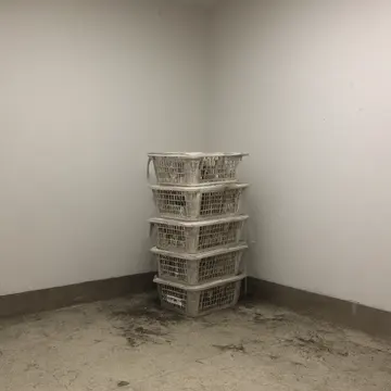 Stack of plastic laundry baskets in Laundry room utility corner. The rhythmic counting of empty, stacked containers. Damp concrete floor tiles