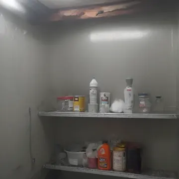 Stack of labeled containers in Utility room corner. A sudden, heavy fog has settled inside the small room. Wet condensation streaks on metal shelving