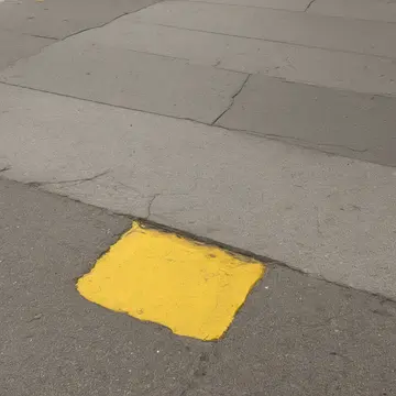 A discarded plastic bottle in Underground transit platform bench. The bottle has settled into a gap between tiles, partially blocking the path. Wet yellow tile grout lines