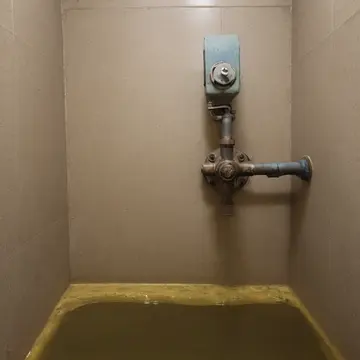 Water fountain dispenser panel in Utility room near public wash station. A minor leak forces repeated activation of a shutoff valve. Dampened paper label on panel