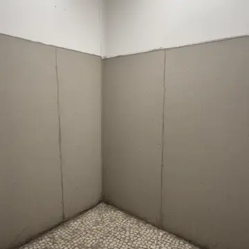 Wet grout line in Subway transfer platform corner. People are walking around it in an established pattern. Scuffed tile baseboard