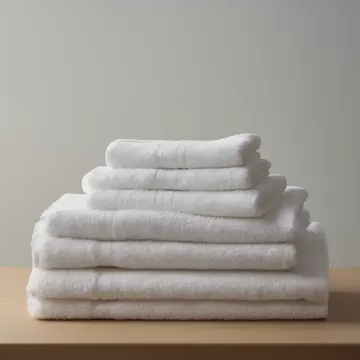 Stacked linen towels in Utility room counter. A careful morning folding routine is interrupted by one towel that refuses to settle flat. Slightly damp soap residue on porcelain