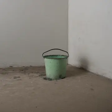 Industrial mop bucket in Utility closet corner. The operator is wiping down a counter that has been cleaned too many times. Wet rubber seal
