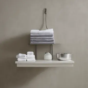 Stack of folded linen towels in Laundry room utility corner. A careful, stalled sorting routine after wash cycle. Lint buildup on metal rack joints