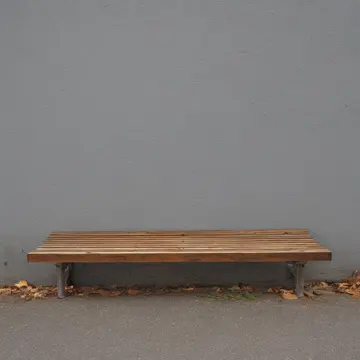 Wooden slat seating in Bus stop shelter bench. Waiting for an unscheduled bus arrival. Wet concrete floor tiles