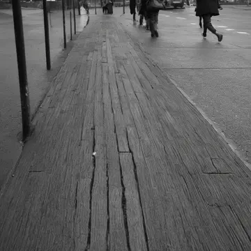 A single leather glove in Bus shelter bench under overhang. Commuters wait quietly for an unseen bus arrival. Wet, dark asphalt curb