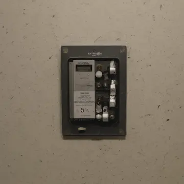 A calibrated junction box cover in Utility closet near municipal records. The operator is performing the final, fifth adjustment on a panel. Yellowed adhesive tape strips