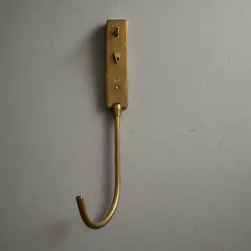 Single brass hook in Department store fitting room area. Closing inspection and minor repair work. Dust on the brass surface